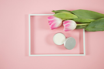 Spa accesories on the pink background with some tulips and facial cream