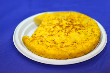 Spanish potato omelette on plastic plate and blue background