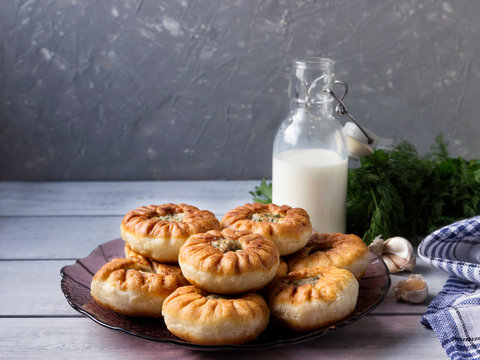 Fried belyashi on a plate and milk in a bottle. Patties with meat and onions.