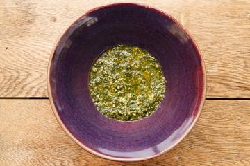 Basil Pesto in Purple Bowl from Top Down on Wooden Table