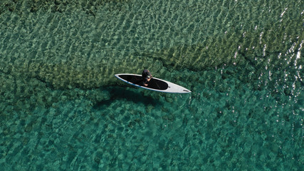 Aerial drone photo of fit man practising Stand Up Paddle or SUP in tropical exotic bay with emerald sea