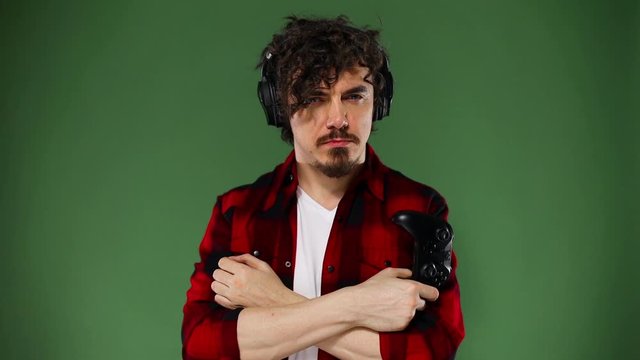 Nerdy gamer with controller on yellow background. Man with curly hair. Chroma key. Slow motion.