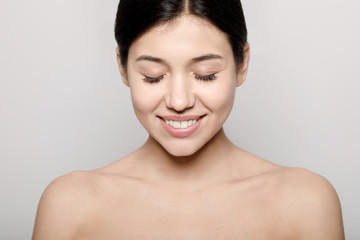 Portrait of cute brunette girl with naked shoulders and eyes closed isolated light background