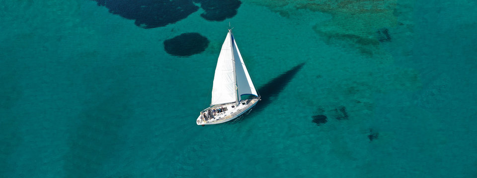 Aerial drone ultra wide photo of beautiful sail boat sailing in tropical exotic bay with emerald clear sea