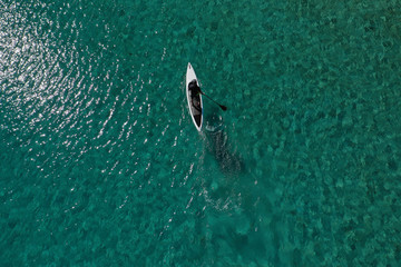 Aerial drone photo of fit man practising Stand Up Paddle or SUP in tropical exotic bay with emerald sea