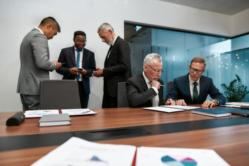 Analyzing documents. Multicultural business team in formal wear discussing something while having a meeting in the modern office. Two business partners reading a contract