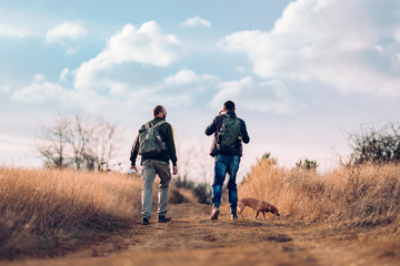 Fototapeta premium Two friends with a dog hiking together