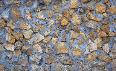 wall of yellow stones of different sizes fastened with gray cement