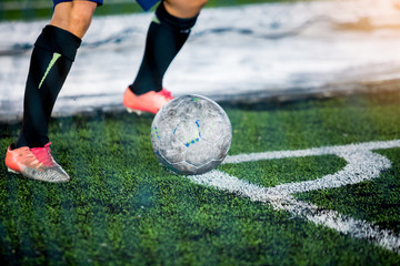 The soccer player shoot ball at corner of football field.