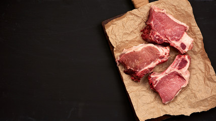 three raw juicy pork slices of meat on the rib