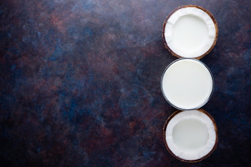 Obraz na płótnie Canvas Coconut milk and coconut in glass on dark background. Coconut vegan milk non dairy with copy space. Healthy drink concept. Alternative milk. Flat lay