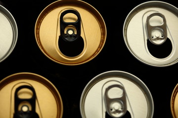 Open cans of beer in yellow and silver color close up