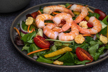 Fresh shrimp and greens salad on dark background