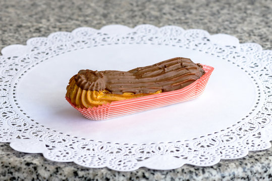 Cake eclair with chocolate cream and milk chocolate cap on a white napkin