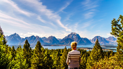 Woman enjoying the view of Jackson Lake and the tall mountain peaks of the Teton Range viewed from Signal Mountain in Grand Teton National Park in Wyoming, United States