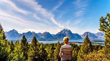 Crédence de cuisine en verre imprimé Chaîne Teton Woman enjoying the view of Jackson Lake and the tall mountain peaks of the Teton Range viewed from Signal Mountain in Grand Teton National Park in Wyoming, United States