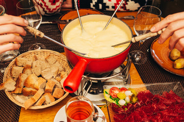 Friends eating cheese fondue in a cozy traditional swiss restaurant - 327434594