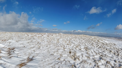 A scenic view of snowy mountain slope under a majestic blue sky and white clouds © Dolwolfian