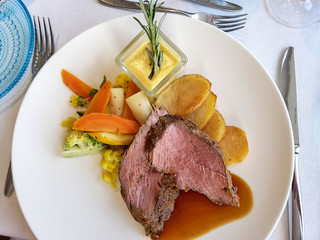 Chateaubriand with colorful vegetables and sliced potatoes on white plate with Bearnaise sauce