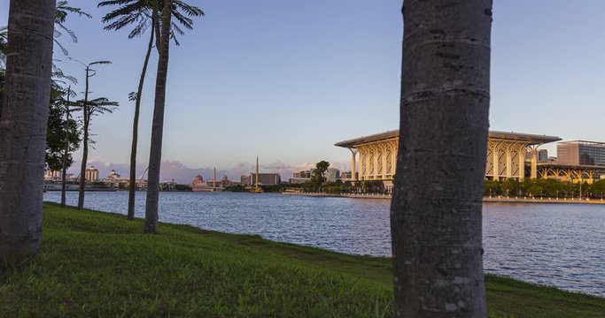 Sunset at the Putrajaya Mosque with view over the Putrajaya lake. Time lapse between trees on a peaceful lake in Malaysia. Captured in a small palm tree forest on the shoreline.