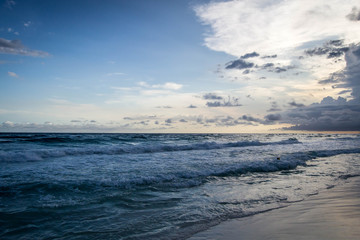 Naklejka na ściany i meble Waves rolling onto the shore during a sunset