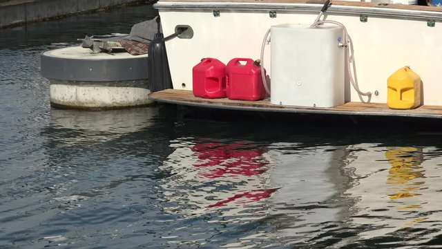 Gas cans on the back of a yacht reflecting into the water of the bay