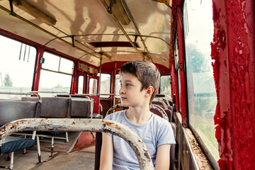 A 10 years boy riding in a old vintage bus, he is sad because his poor life and the bus moving going on a dirty country road © ReaLiia