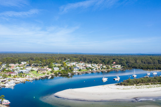 Aerial drone view of Huskisson on the New South Wales South Coast, Australia, showing Currambene Creek and Jervis Bay on a bright sunny day   