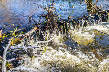 Dam in winter with frozen waterfall and icicles on the river