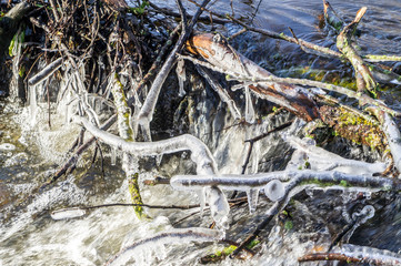 Dam in winter with frozen waterfall and icicles on the river