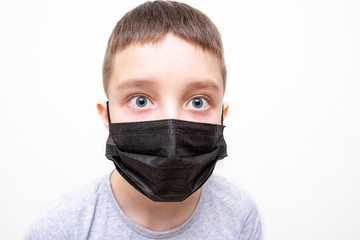 A portrait of a boy wearing surgical medical black face mask on white background
