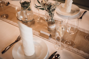 Detail of a set table in a rustic style with a sackcloth, tablecloth and white lace. Image with shallow depth of field. Focus on blank guest tag (text can be added).