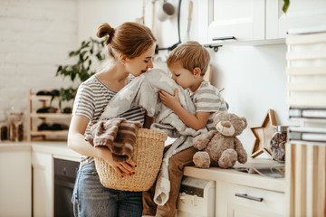 Happy family mother housewife and child   in laundry with washing machine .