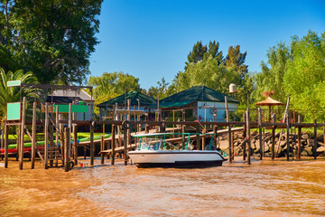 Tigra delta in Argentina, river system of the Parana Delta North from capital Buenos Aires. Lush vegetation, wooden houses. Motor boat by wooden pier.