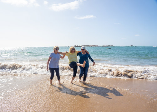 Group of three senior women walking having having fun on beach. Friendship and healthy lifestyle