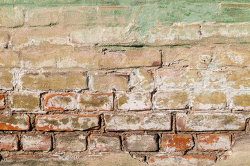 Old weathered brick wall. Peeling cracked paint on red brick