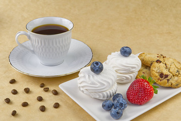 white coffee cup with a gold rim breakfast, coffee and bize cookies with raspberries and blueberries