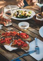 Dinner with salad, bruschetta with tomato and white wine in summer open-air cafe in Italy, selective focus. Travel, wanderlust, Italian lifestyle concept