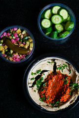 Muhammara hummus with salad and cucumber slices.
