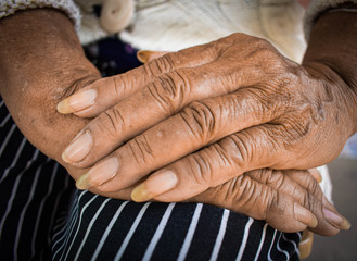 Fototapeta premium Old woman with wrinkles with clearly visible wrinkles, putting her hands on the lap