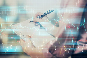 Multi exposure of hands making notes with forex chart huds. Stock market concept.