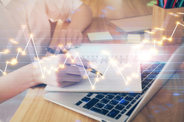 Financial charts displayed on woman's hand taking notes background. Concept of research. Double exposure