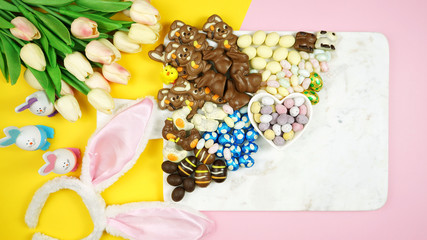 Obraz na płótnie Canvas Colorful Happy Easter chocolate and candy eggs and bunnies dessert grazing platter charcuterie board. Negative copy space.