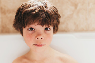 Portrait of a young boy sitting in a bubble bath