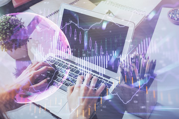 Double exposure of stock graph with businessman typing on computer in office on background. Concept of hard work.