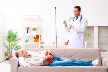 Young male doctor visiting old patient at home