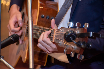 Close-up on hand, A handsome young man plays the guitar for a live performance on stage