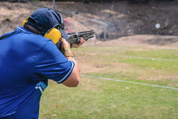 selective focus of man holding and fire shortgun in shooting range of gun shooting competition