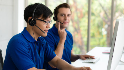 business background of asian and caucasian male customer service agents on telephone service to customers at helpdesk call center and customer service operation center - obrazy, fototapety, plakaty