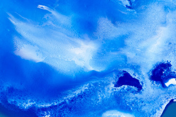Fototapeta na wymiar Classical blue and white watercolor paint in abstract spreading forms similar to satellite imagery with arctic snow hills and seas with glaciers melting in macro. Stains of paint in macro for design.